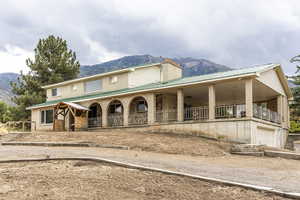 View of front of property featuring a mountain view, a metal roof, a large porch, and a garage