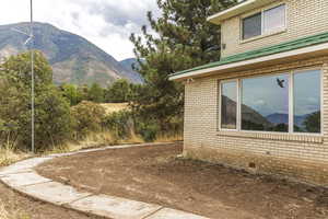 View of property exterior featuring a mountain view, brick siding, and a patio