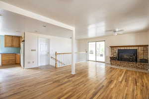 Unfurnished living room with a textured ceiling, light wood-type flooring, a wood stove, and ceiling fan