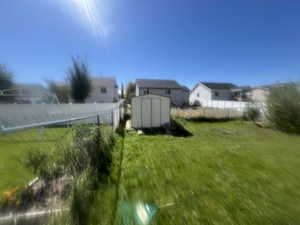 Fenced backyard featuring a shed