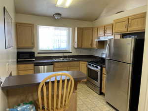 Kitchen with stainless steel appliances, dark countertops, a peninsula, a textured ceiling, and under cabinet range hood