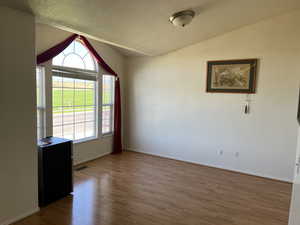 Unfurnished room with lofted ceiling and wood finished floors