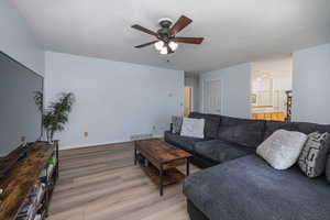 Living area featuring light wood-style flooring, ceiling fan, and a textured ceiling