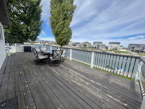 Wooden deck featuring an outdoor dining area, a water view, and area for grilling