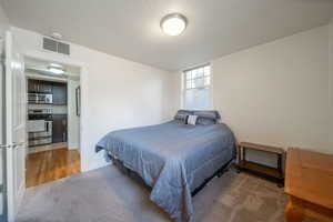 Bedroom with light carpet and a textured ceiling