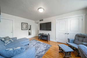 Living area featuring light wood-style floors and a textured ceiling
