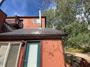 View of property exterior featuring a metal roof and a wooden deck