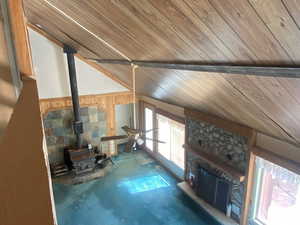Living area with lofted ceiling, a fireplace, a wood stove, wood walls, and wood ceiling