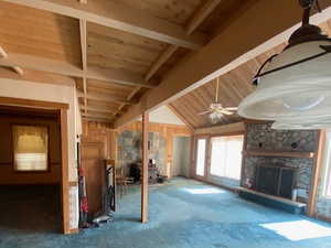 Unfurnished living room featuring a fireplace, carpet floors, wooden ceiling, and a ceiling fan