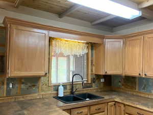 Kitchen with a wooden ceiling with exposed beams and light brown cabinetry