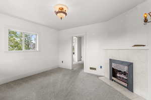 Unfurnished living room featuring a tile fireplace and carpet flooring
