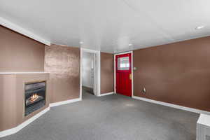 Carpeted entryway featuring a warm lit fireplace and recessed lighting
