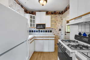 Kitchen with white appliances, white cabinetry, tasteful backsplash, and open shelves