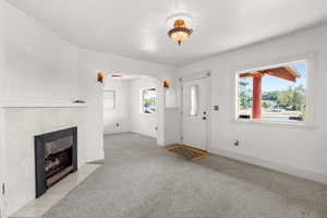 Foyer entrance with healthy amount of natural light, a tiled fireplace, and carpet flooring