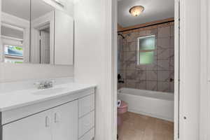 Bathroom featuring vanity, shower / bath combination, and plenty of natural light