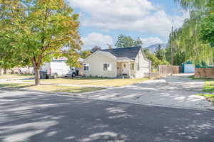 View of front of home with an outbuilding, a garage, covered porch, and roof with shingles