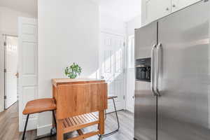 Kitchen with stainless steel fridge, light wood finished floors, and white cabinetry