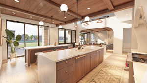 Kitchen with light wood finished floors, a kitchen island with sink, pendant lighting, plenty of natural light, and a wooden ceiling with exposed beams