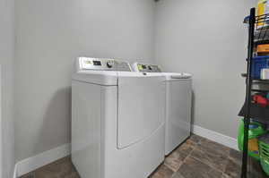Laundry area featuring separate washer and dryer and dark stone finish floors