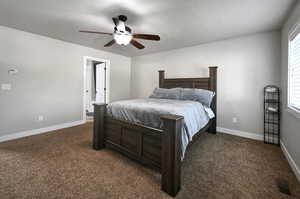 Bedroom featuring dark colored carpet, ceiling fan, multiple windows, and a textured ceiling