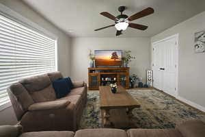 Living area featuring a ceiling fan and baseboards