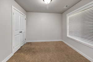 Unfurnished bedroom featuring carpet, a closet, and a textured ceiling