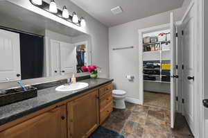 Main Bedroom on suite with a spacious closet, vanity, and dark stone finish flooring