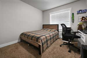 Carpeted bedroom featuring baseboards and an office area