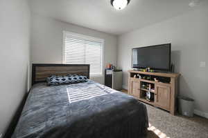 Carpeted bedroom featuring baseboards and stainless steel fridge