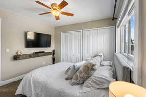 Carpeted bedroom with two closets and ceiling fan