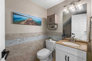 Bathroom with tile walls, vanity, and wainscoting