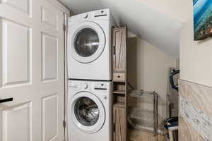 Laundry area with a textured ceiling and estacked washer and dryer