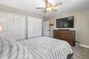 Bedroom with multiple closets, carpet flooring, and ceiling fan