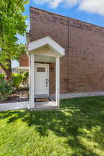 Property entrance with a lawn and brick siding