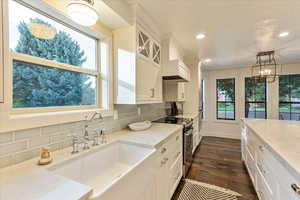 Kitchen with black range with electric cooktop, glass insert cabinets, white cabinetry, and recessed lighting