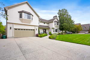 View of front of home with driveway, brick siding, an attached garage, a front yard, and stucco siding