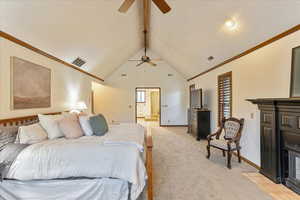 Bedroom featuring ornamental molding, beamed ceiling, high vaulted ceiling, a fireplace with flush hearth, and light carpet