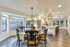 Dining area with a textured ceiling, a chandelier, dark wood-type flooring, and recessed lighting