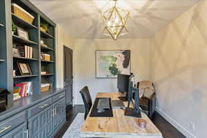 Home office with dark wood-style flooring and a chandelier