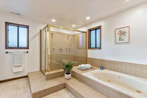 Bathroom featuring a shower stall, a jetted tub, recessed lighting, and light tile patterned floors