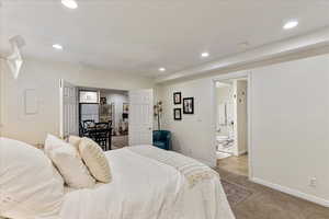 Bedroom featuring recessed lighting, carpet flooring, freestanding refrigerator, electric panel, and ensuite bath