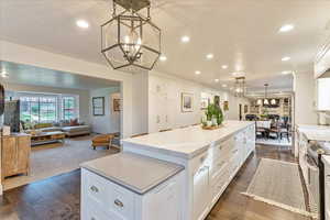 Kitchen featuring open floor plan, white cabinetry, pendant lighting, dark wood-type flooring, and stainless steel range with electric cooktop