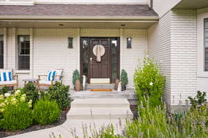 Doorway to property featuring brick siding and roof with shingles