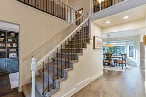 Stairway with hardwood / wood-style flooring, a high ceiling, and recessed lighting