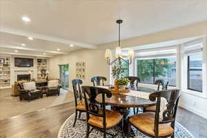 Dining space with beam ceiling, a fireplace, dark wood-type flooring, built in features, and recessed lighting