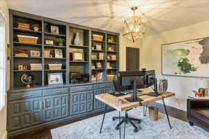 Home office with dark wood-type flooring and a chandelier