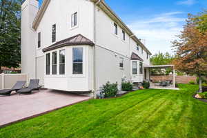 Back of property with a patio, stucco siding, a standing seam roof, a chimney, and a metal roof