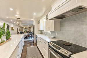 Kitchen with premium range hood, appliances with stainless steel finishes, light stone countertops, recessed lighting, and white cabinets