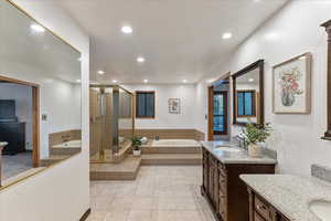 Bathroom with two vanities, a bath, a shower stall, recessed lighting, and light tile patterned floors