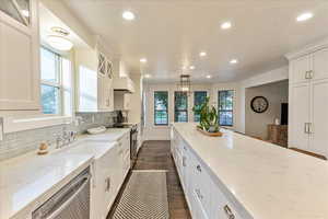 Kitchen featuring light stone countertops, decorative backsplash, dark wood-type flooring, recessed lighting, and appliances with stainless steel finishes